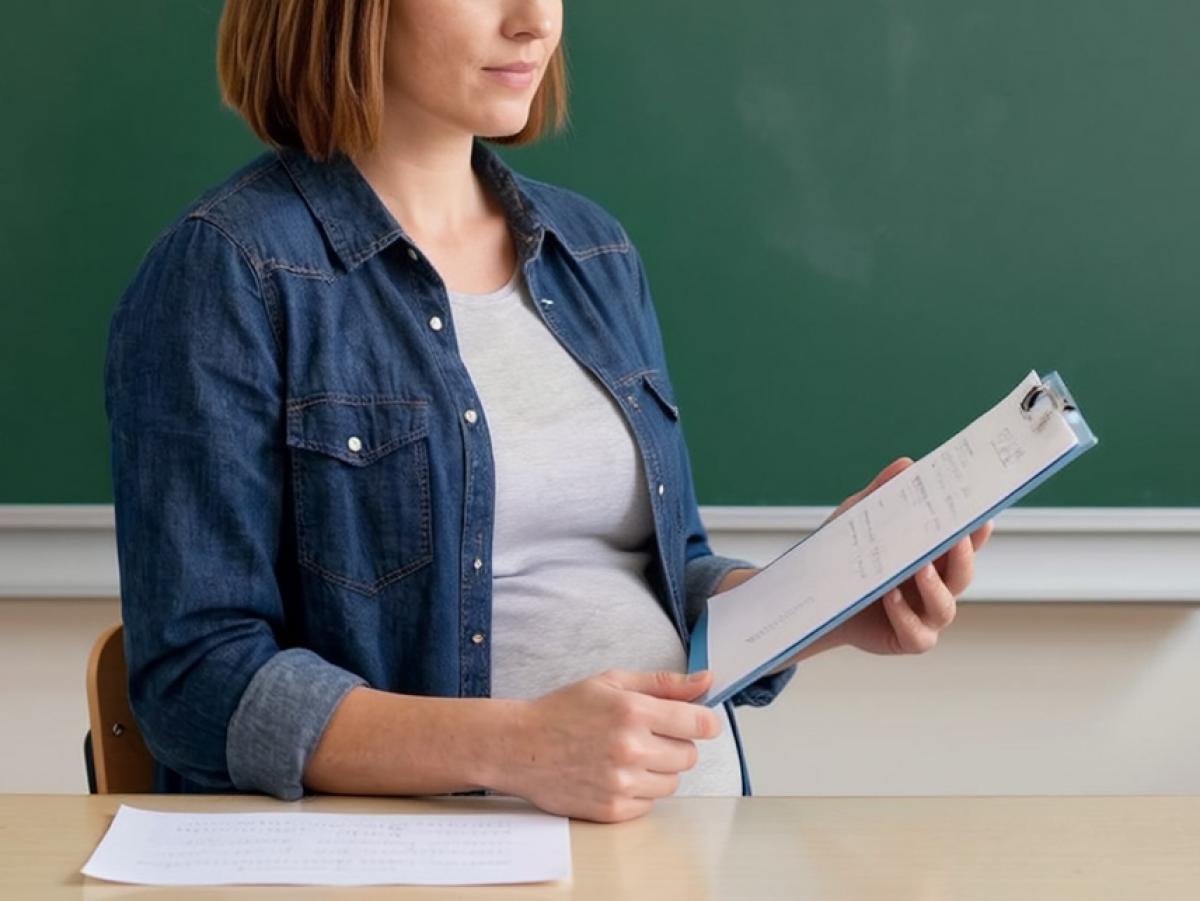Maestra embarazada sentada.